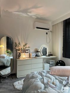 a bedroom with a bed, dresser and mirror on it's side in front of a window