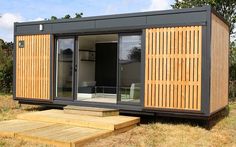 a tiny house made out of shipping containers with sliding doors on the outside and steps leading up to it