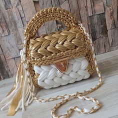 a white and gold purse sitting on top of a wooden table next to a wall