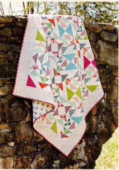 two quilts are hanging on a stone wall