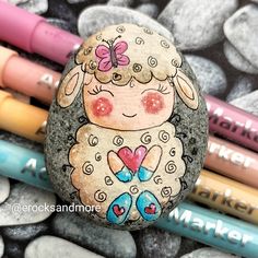 a rock with a sheep painted on it next to crayons