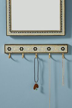 a mirror hanging on the wall next to a necklace holder