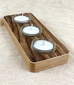 three candles are sitting in a wooden holder