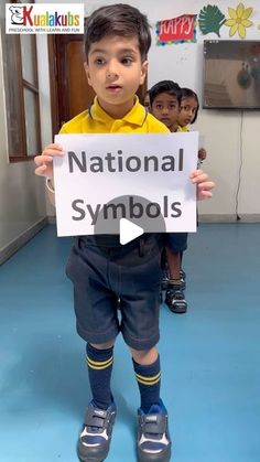 a young boy holding up a sign with the words national symbols on it in front of him