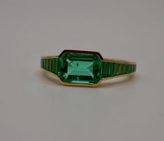 Lower prices and more options on our main website: www.shopdiscomarshmallow.com At the centerpiece of this lab grown Colombian emerald ring is a radiant 1.5 ct emerald, set east west to highlight its natural allure. Flanking it are calibre cut emeralds, each uniquely shaped to create a seamless gradient effect, making every ring truly one-of-a-kind. Set in luxurious 18K yellow gold, this ring exudes timeless charm.  What makes it truly special? Calibre cut stones are individually shaped to fit p Columbian Emerald Ring, Formal Channel Set Emerald Ring, Formal Green Channel Set Emerald Ring, Channel Set Emerald Cut Emerald Ring, Emerald Cut Emerald Ring Channel Set, Emerald Cut Channel Set Emerald Ring, Classic Green Channel Set Ring, Classic Baguette Cut Green Emerald Ring, Classic Green Baguette Cut Emerald Ring