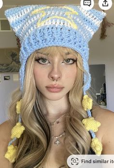 a woman with long blonde hair wearing a blue and yellow crochet cat hat