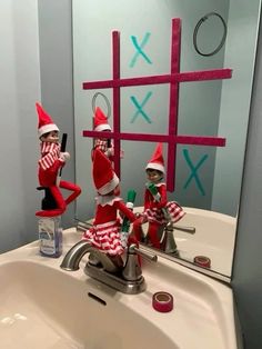 two elfs in red and white outfits are sitting on the sink