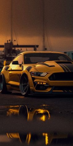 a yellow sports car parked in front of a boat at night with the sun setting behind it