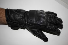 a man's black leather gloves on top of a white table next to a wall