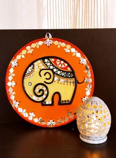 an orange plate sitting on top of a table next to a white vase and lamp