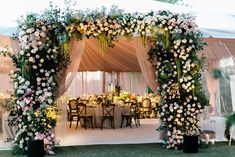 an outdoor tent with tables and chairs covered in flowers