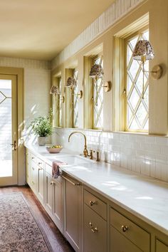 a kitchen with white counter tops and gold fixtures on the cabinets, along with a rug