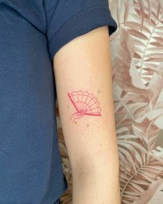 a woman's arm with a tattoo that has a red design on the side