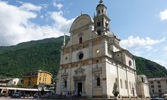 an old church in the middle of town with mountains in the backgrouds