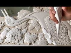 a person is working on an intricately designed wallpaper with white flowers and leaves