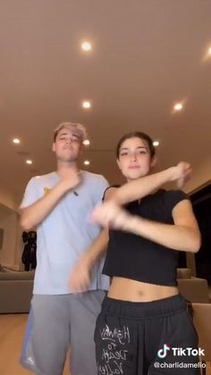 two people are standing in a room with lights on the ceiling and one person is dancing