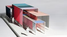 an architectural model of a multi - colored building with people walking around it on a white surface