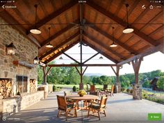 an outdoor dining area with tables and chairs under a wooden roof over looking the countryside