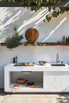 an outdoor kitchen with sink, counter and potted plants on the wall behind it