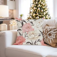 a living room with a christmas tree in the background and flowers on the pillow cover