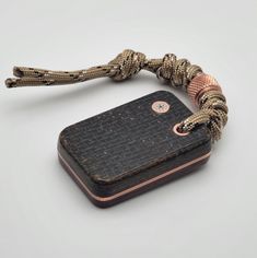 a snake skin bracelet with a metal box on the side and a rope attached to it