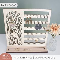 the laser cut card is displayed next to a vase with flowers and earrings on it