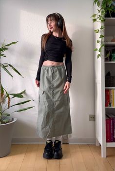 an outfit with a cargo skirt, chunky black boots, crop top & headphones