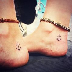 two people with matching tattoos on their feet, one has an anchor and the other has a cross