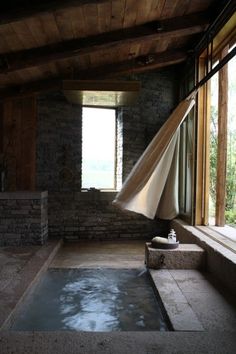 an indoor hot tub in the middle of a room with stone walls and flooring