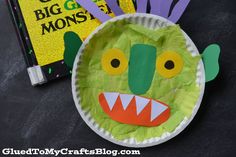 a paper plate with a monster face on it next to a book and some scissors