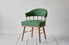 a green chair sitting on top of a wooden floor next to a white wall in an empty room