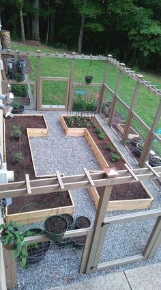 an outdoor garden area with various plants in the ground and fenced in areas around it