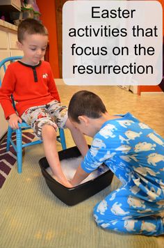 two young boys sitting on the floor playing with sand and water in a black container