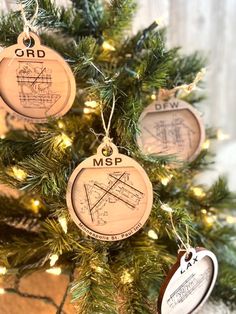 three wooden ornaments hanging from a christmas tree with string lights around them and an ornament that says, msp