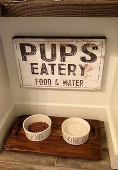 two white bowls with food in them sitting on a wooden tray next to a sign that says pup's eatery