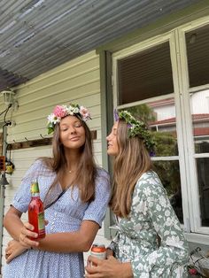 two young women standing on the porch with drinks in their hands and looking at each other