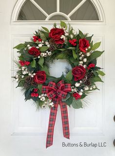 a wreath with red roses and greenery is hanging on the front door for christmas