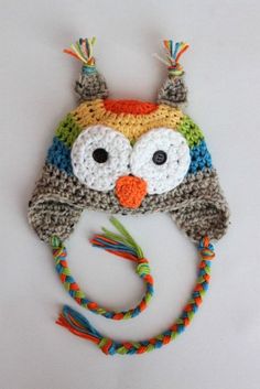 a crocheted owl hat with multicolored braids on it's brim