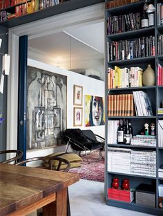 an open book shelf filled with books next to a dining room table and chairs in front of it