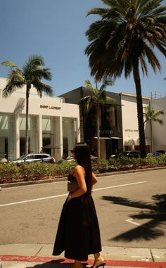 a woman is walking down the street talking on her cell phone while wearing a black dress