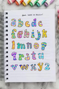 an open notebook with colorful letters and numbers on it next to colored crayons