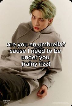 a man with green hair sitting on the ground in front of a white background and text that reads, are you an umbrella? cause i need to be under you rainy rizza