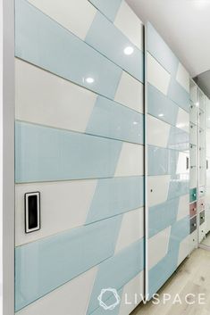 an office hallway with blue and white tiles on the wall behind glass partitions that lead into another room