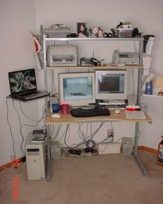 a computer desk with two monitors and a laptop on it in a room that has carpeted flooring