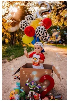 a little boy is sitting in a box with balloons and numbers on the ground next to him