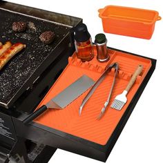 an outdoor grill with hot dogs and other cooking utensils on it's tray