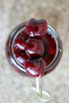 three cherries on a stick in a glass jar