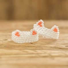 two white and orange beaded shoes sitting on top of a wooden table