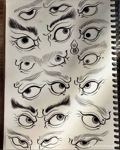 an open notebook with various drawings of eyes and eyelashes on the pages, all drawn in black ink