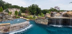 an outdoor swimming pool with waterfall and rock walls